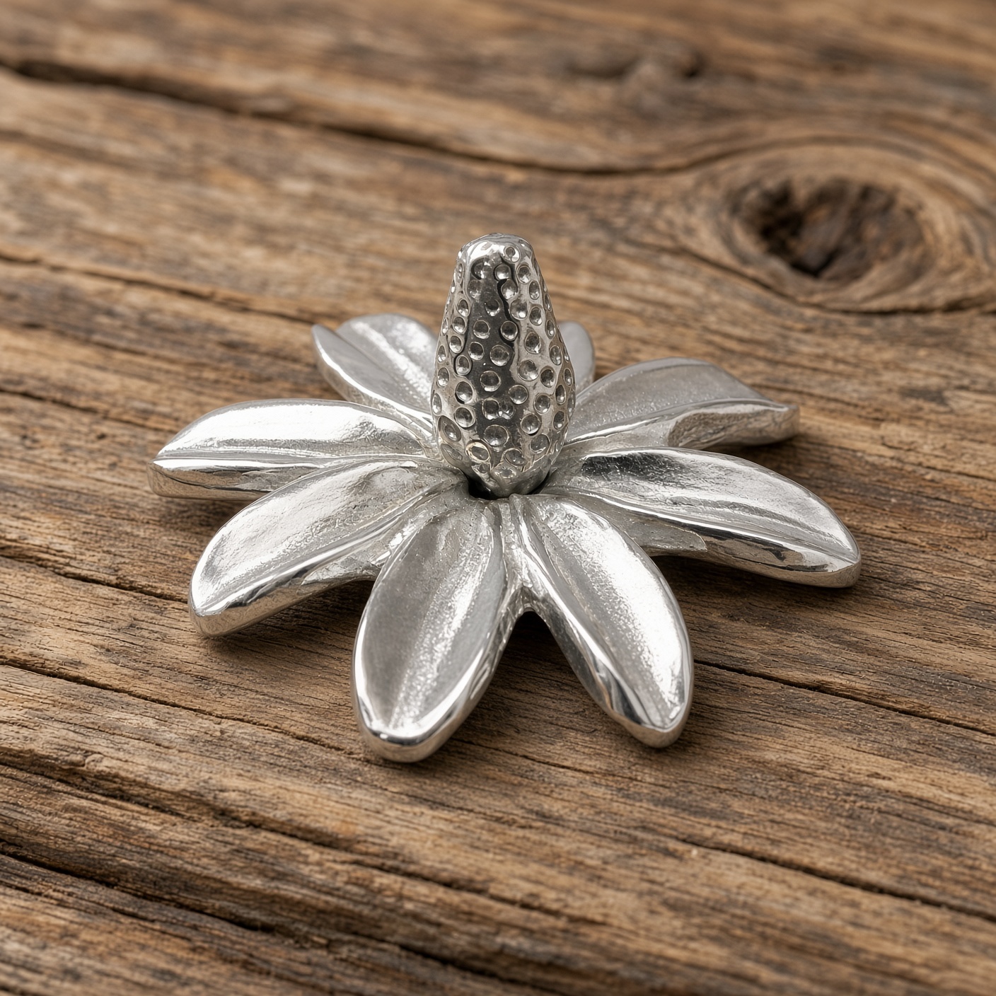 Pewter daisy ring holder on a wood surface