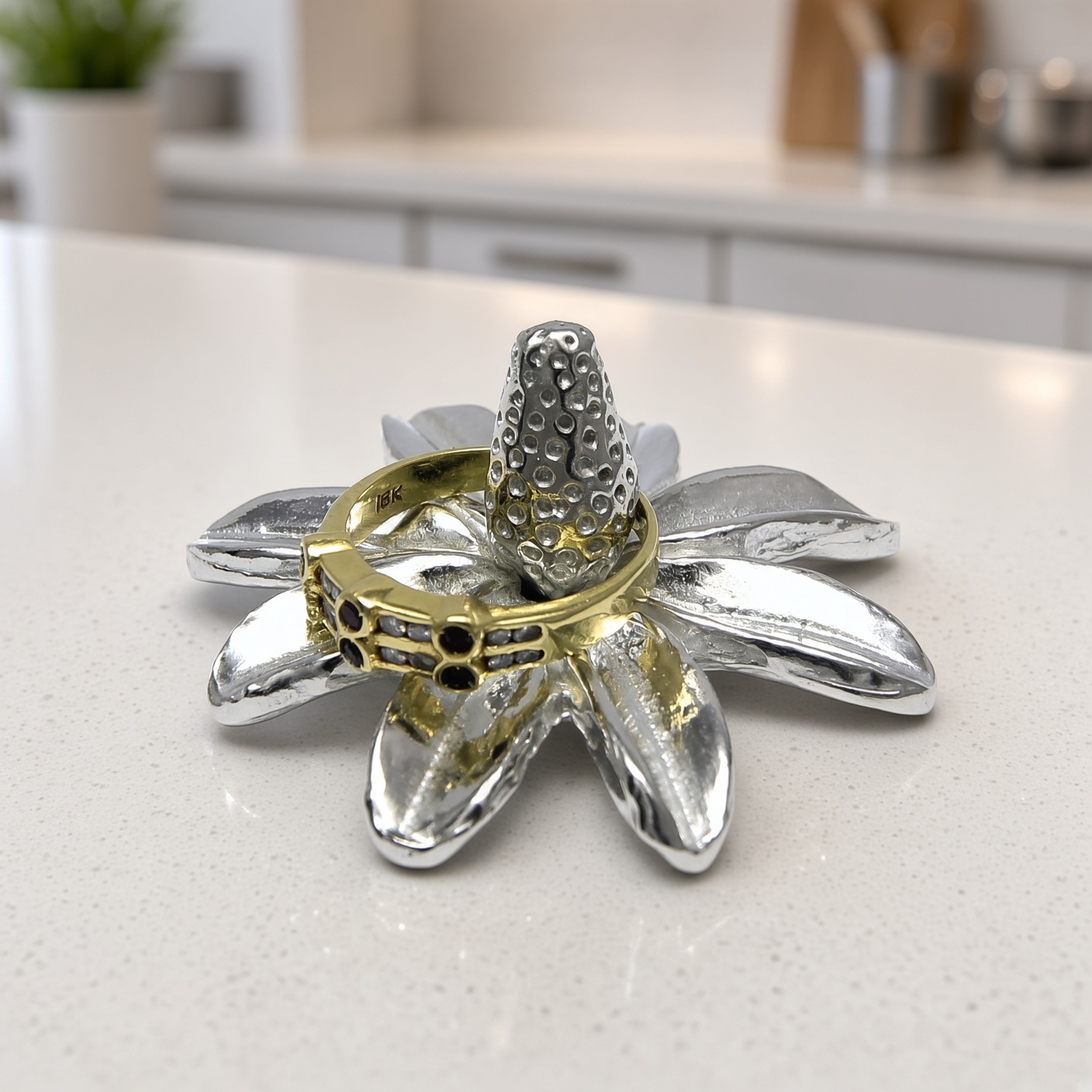 Pewter daisy ring holder holding a gold ring on a kitchen counter, ring not included