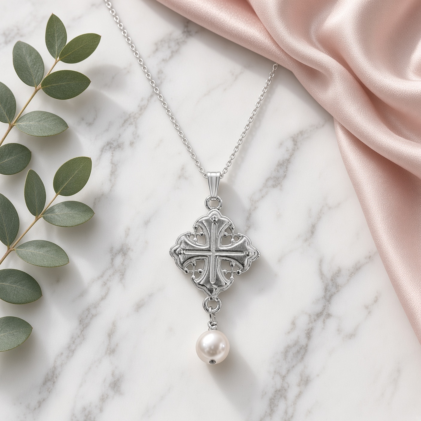 Sterling silver Byzantine cross and pearl necklace on white marble with blush satin and eucalyptus