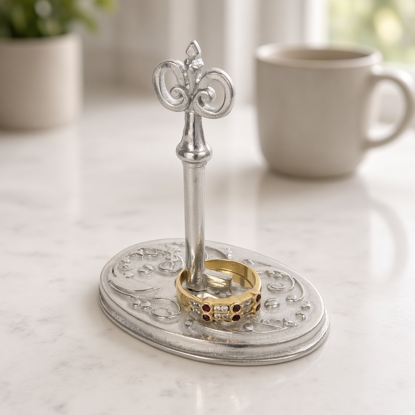 Pewter key ring holder with a gold ring resting on the base around the key shaft, on a marble counter beside a mug, ring not included