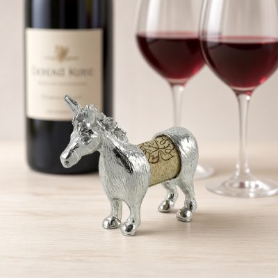 Lucina K Donkey Cork Pet, a solid pewter donkey with tall ears holding a wine cork, beside a wine bottle and two glasses of red wine