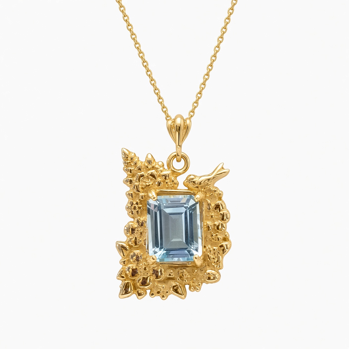 14K yellow gold pendant with an emerald-cut sky blue topaz framed by sculpted flowers and a small bird, on a gold chain, white background