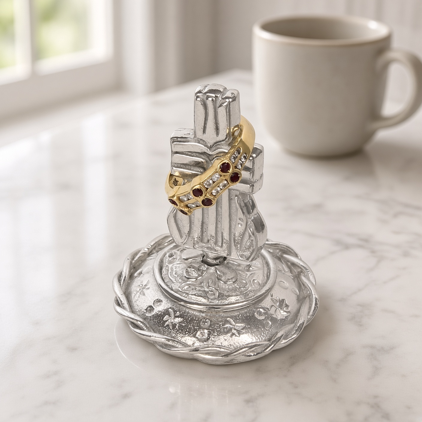 Pewter Presbyterian cross ring stand with a gold ring hanging on the cross arm on a marble counter beside a mug, ring not included