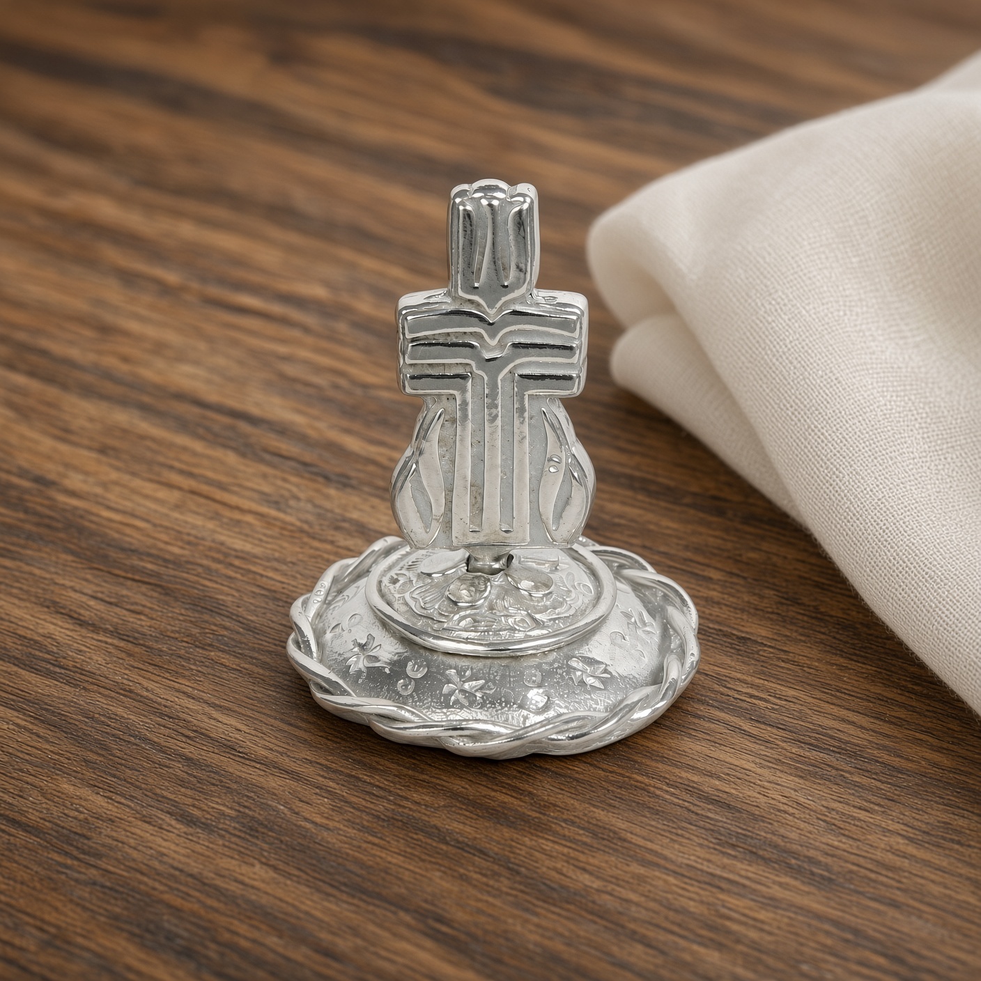 Pewter Presbyterian cross ring stand on a wood table with a cream napkin