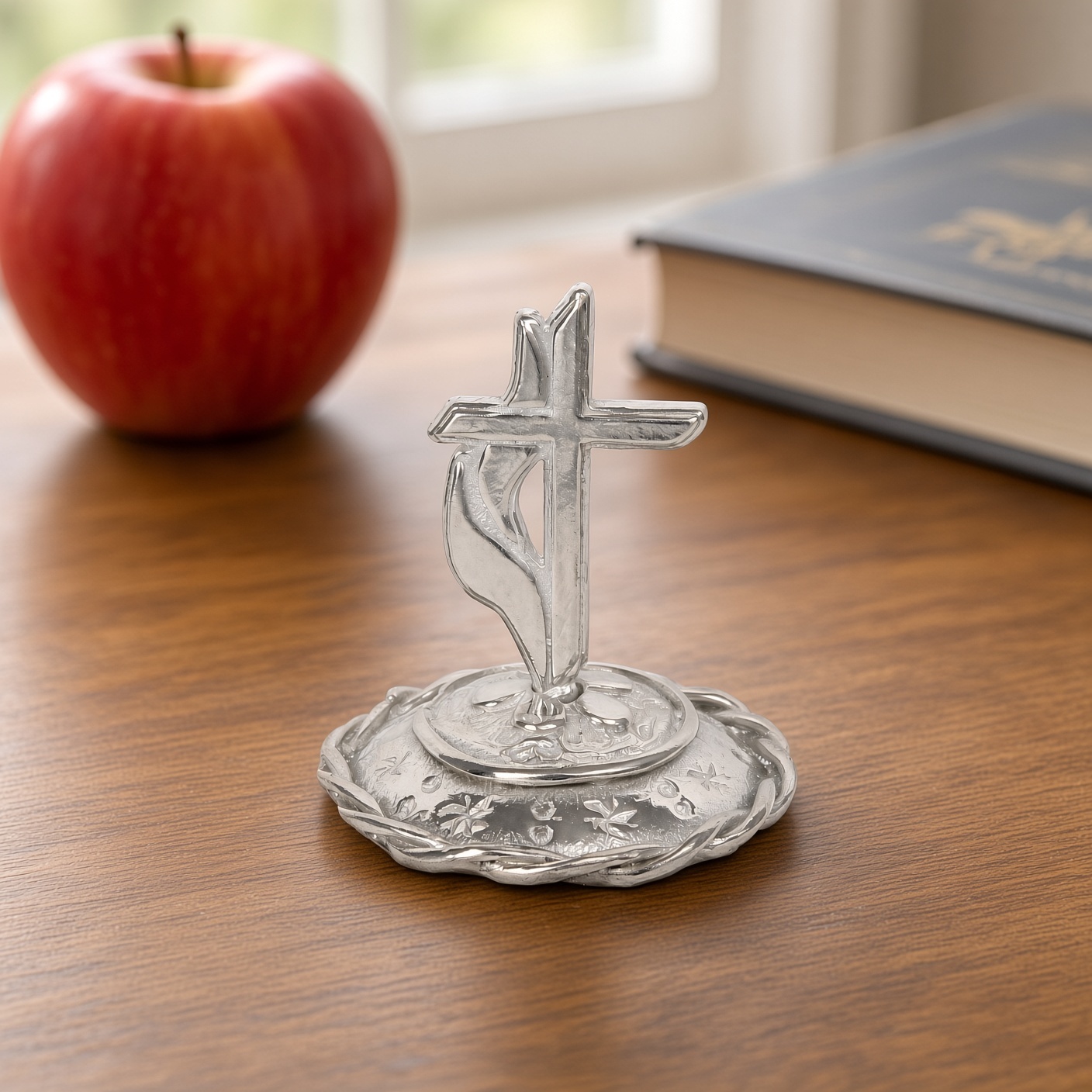 Pewter Methodist cross ring stand on a desk with a red apple and a book