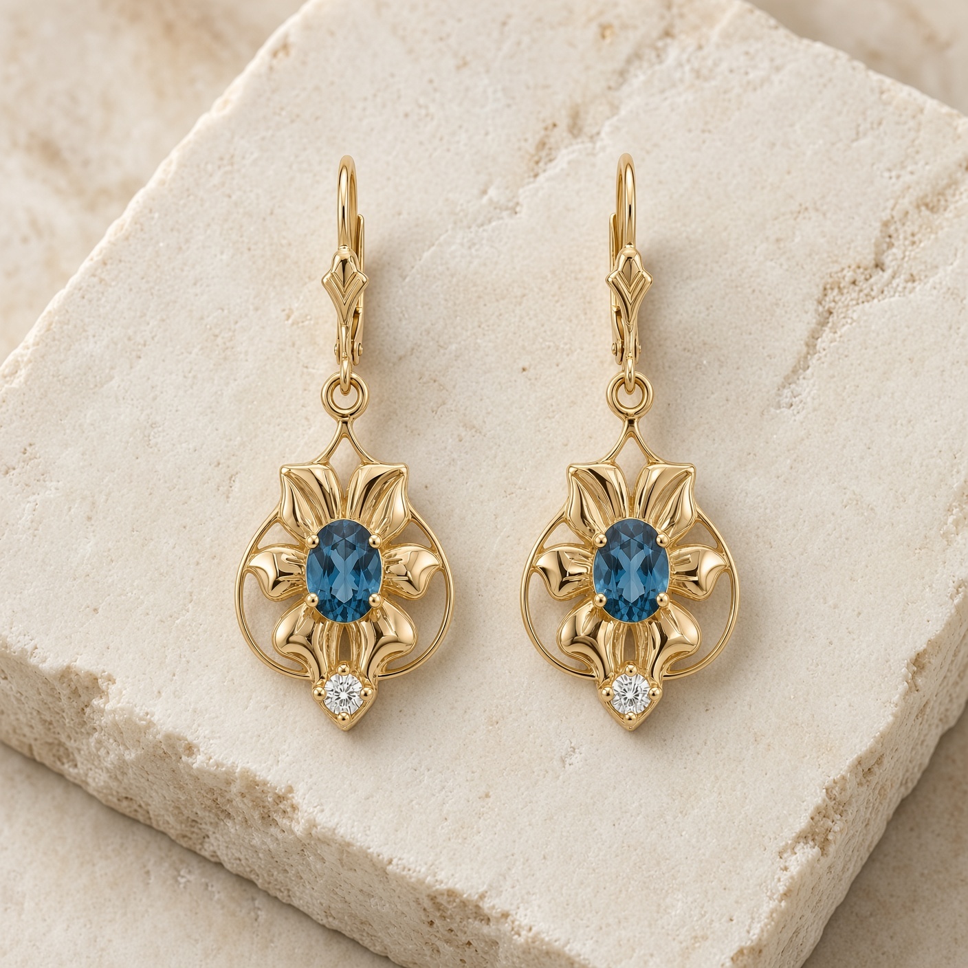 London blue topaz and diamond flower earrings in 14K yellow gold on a pale stone slab