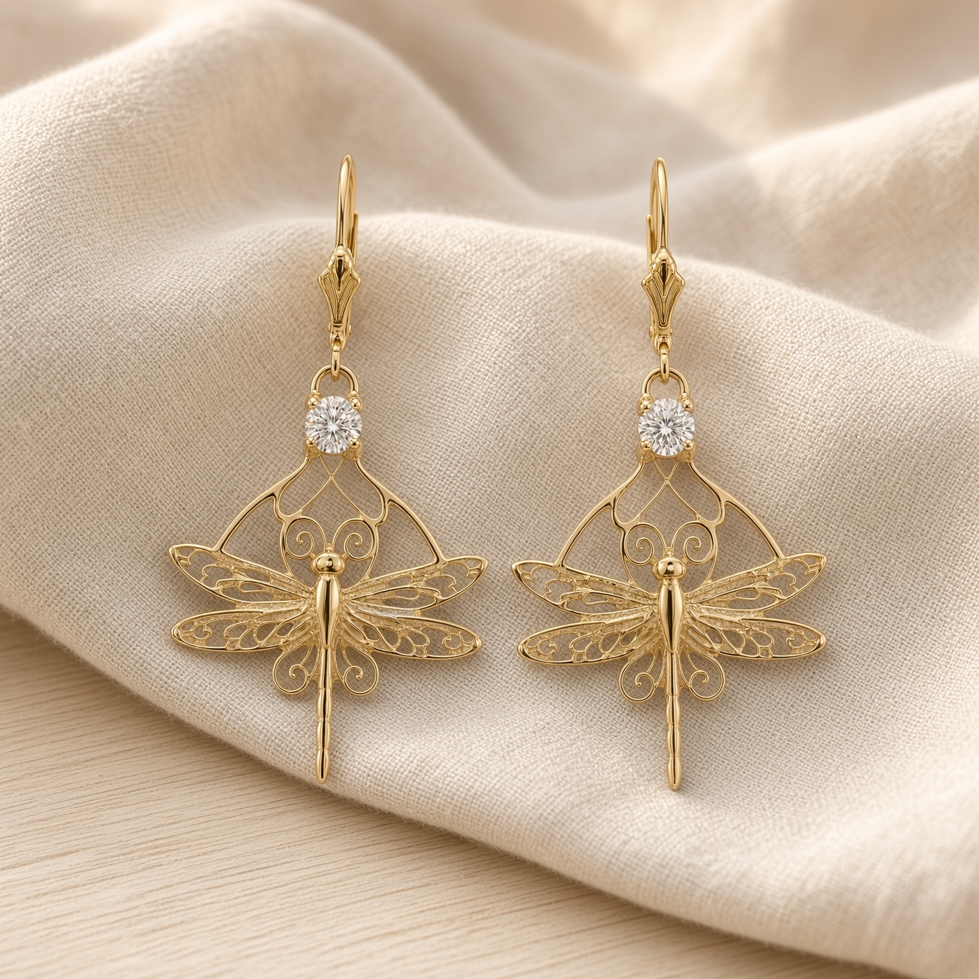 Art nouveau dragonfly earrings in 14K gold with diamonds laid on soft draped ivory fabric