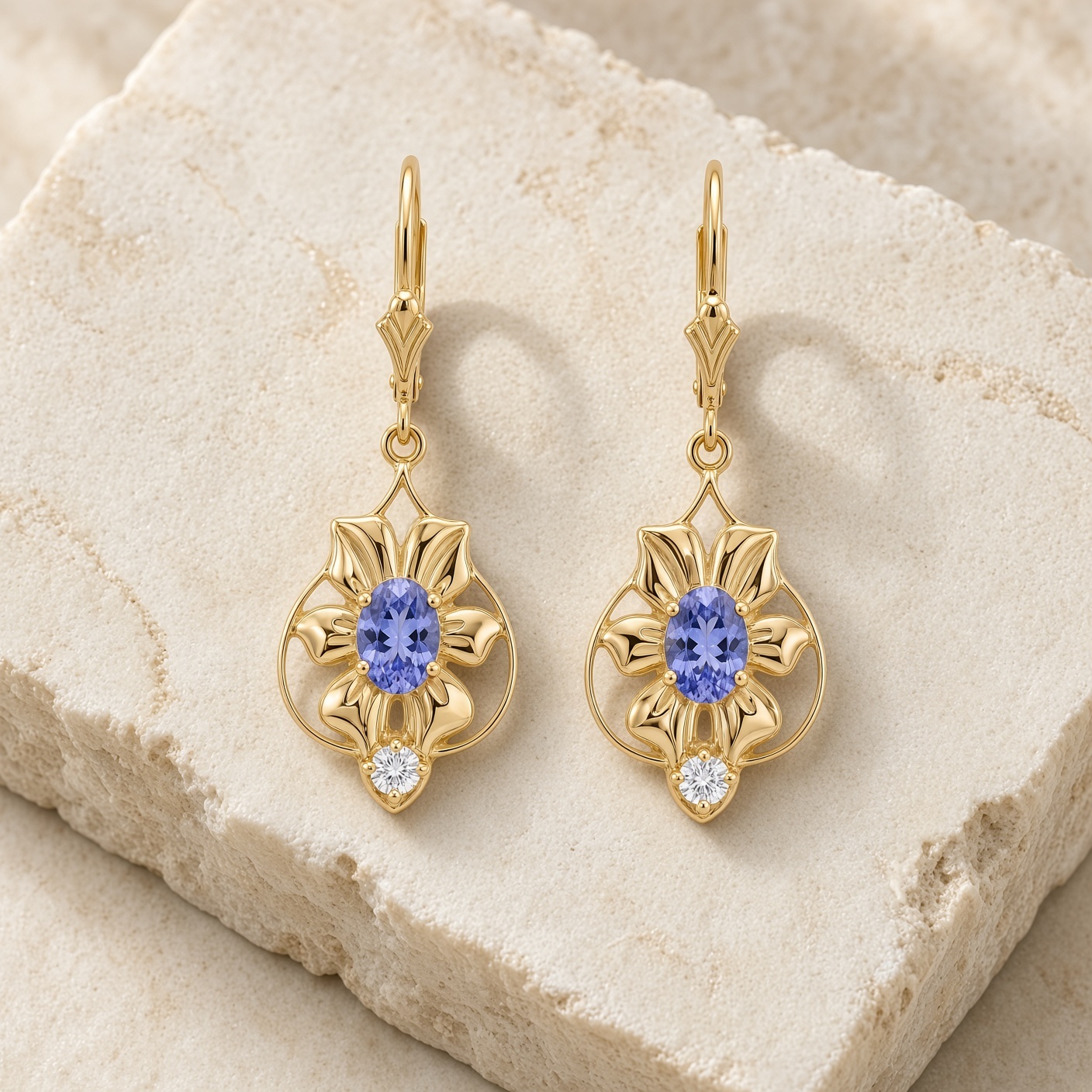 Tanzanite and diamond flower earrings in 14K yellow gold on a pale stone slab