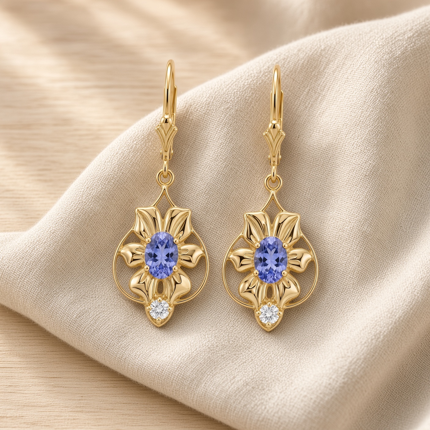 14K gold flower earrings with oval tanzanites and diamond accents on soft cream linen